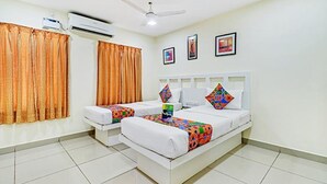 A hotel room with two beds, an air conditioning unit, a ceiling fan, and a tiled floor.