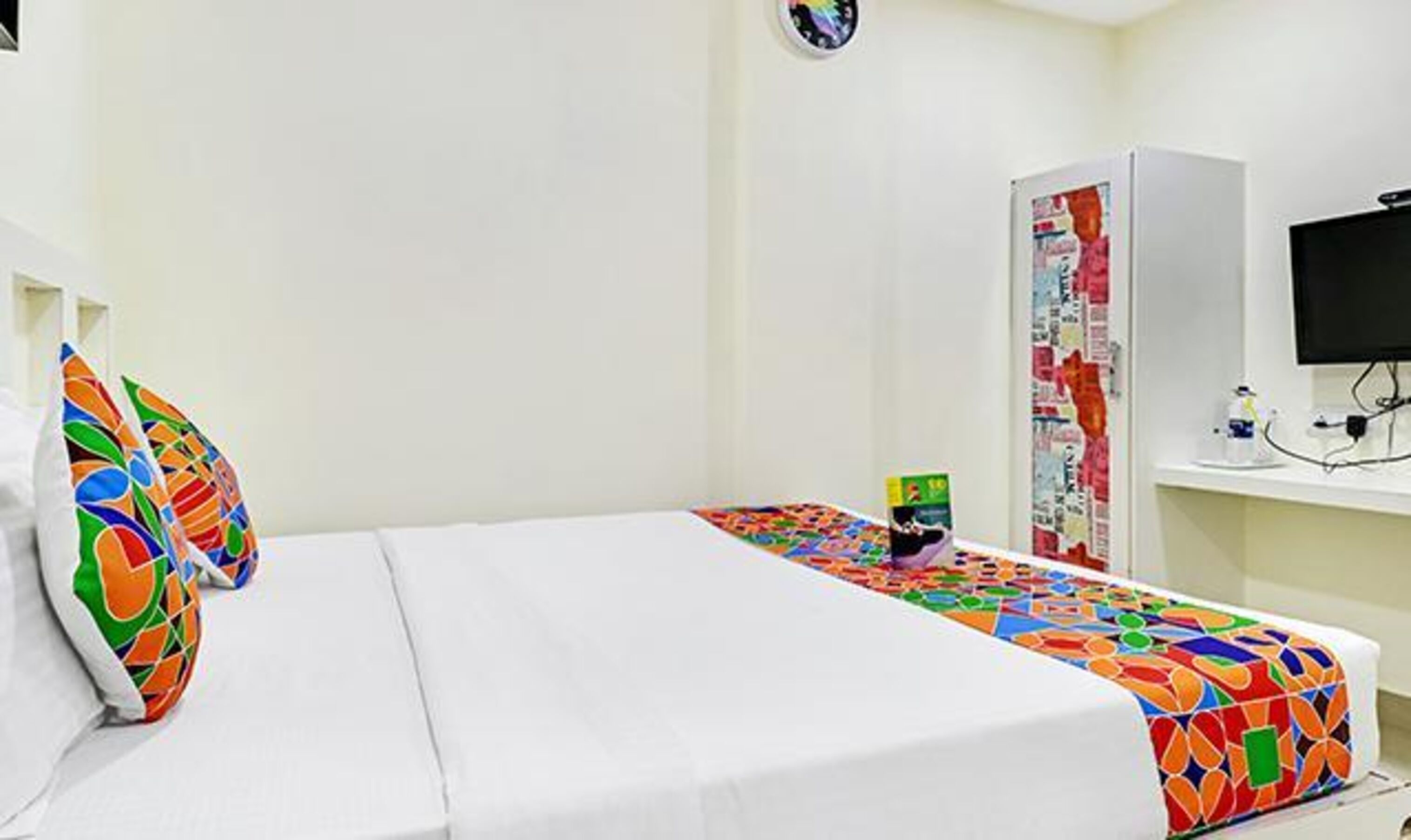 Una habitación de hotel con una cama, un televisor y un escritorio con un ordenador.