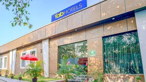 Un hôtel avec une enseigne indiquant « fabHOTELS » et une grande fenêtre donnant sur des arbres.