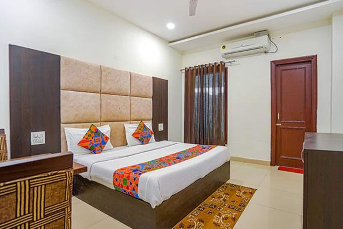 Una habitación de hotel con cama, escritorio, armario y aire acondicionado.