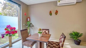 Un coin repas avec une table et des chaises, une plante en pot et un climatiseur fixé au mur.