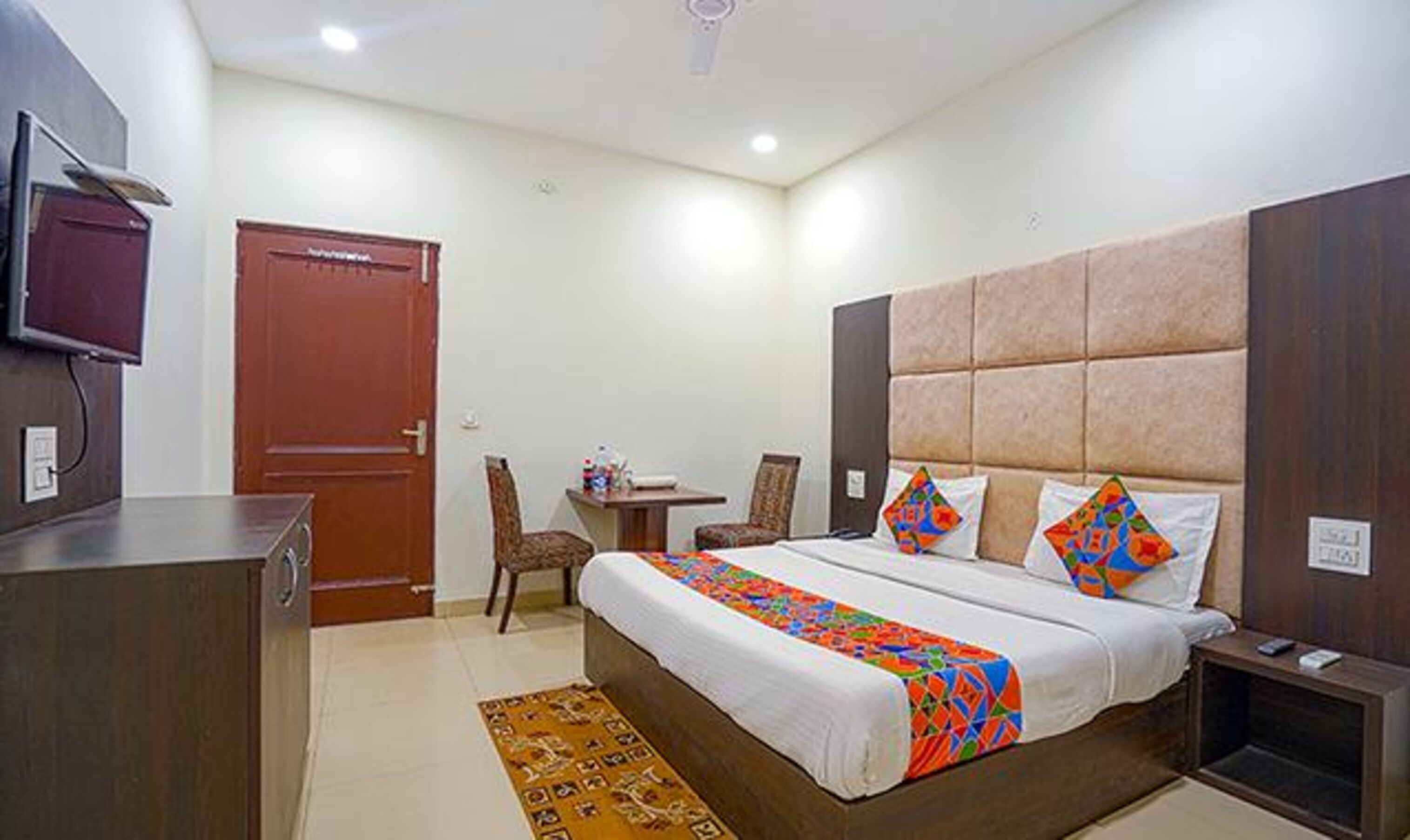 A hotel room with a bed, a desk, a chair, and a television.