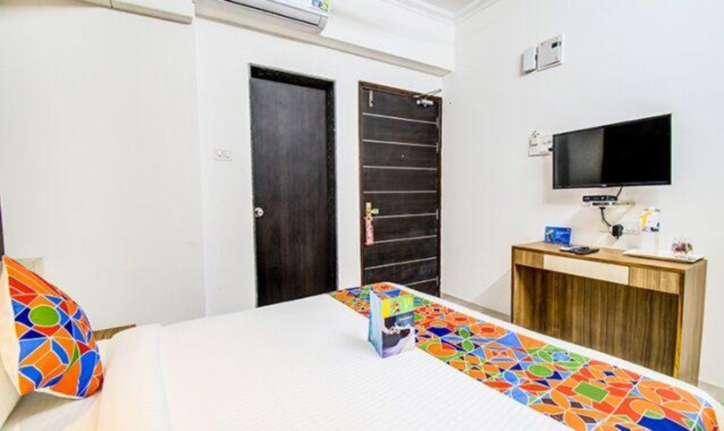 Une chambre d’hôtel avec un lit, un bureau, une télévision et deux portes.