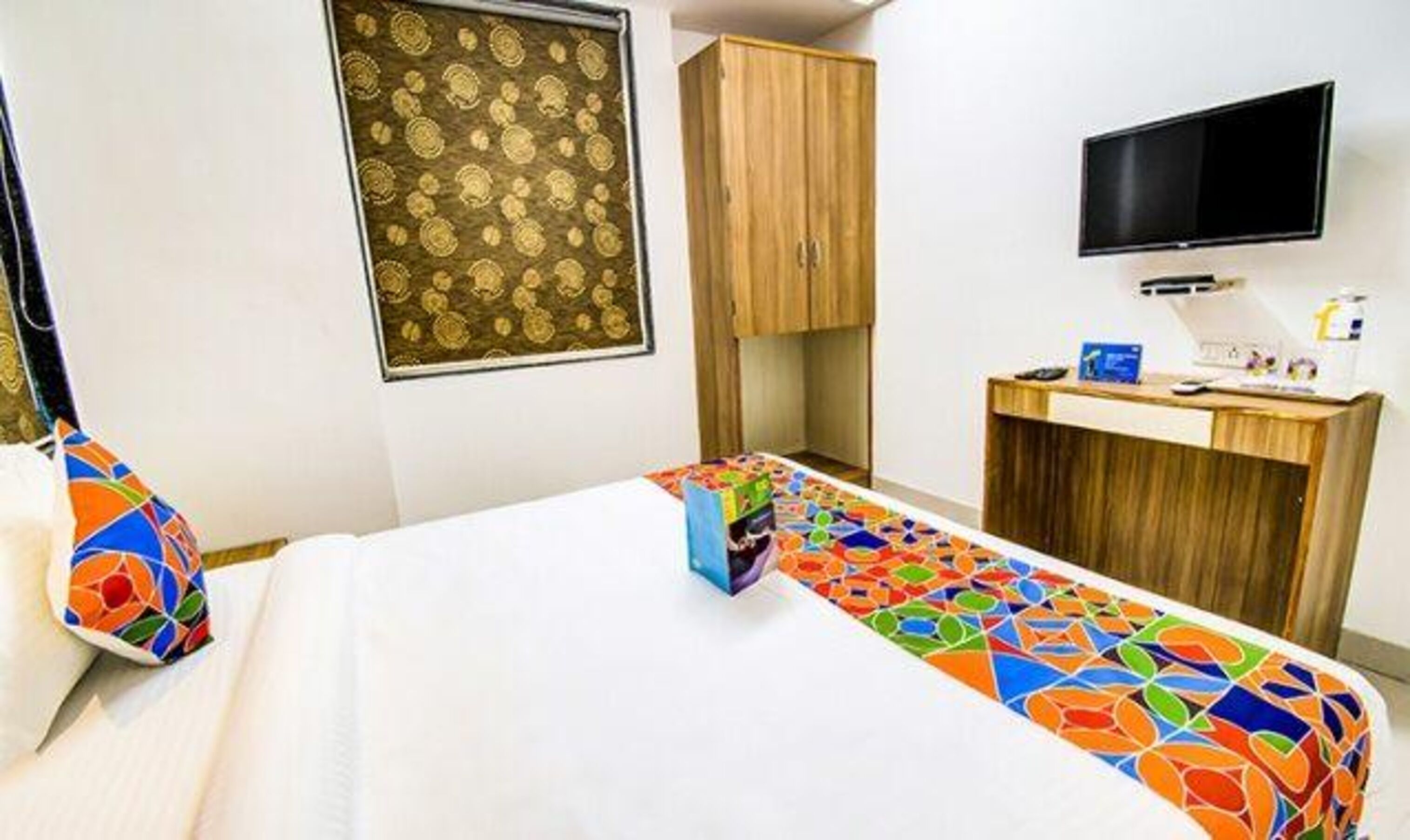 A hotel room with a bed, a desk, a television, and a wardrobe.