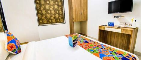 A hotel room with a bed, a desk, a television, and a wardrobe.