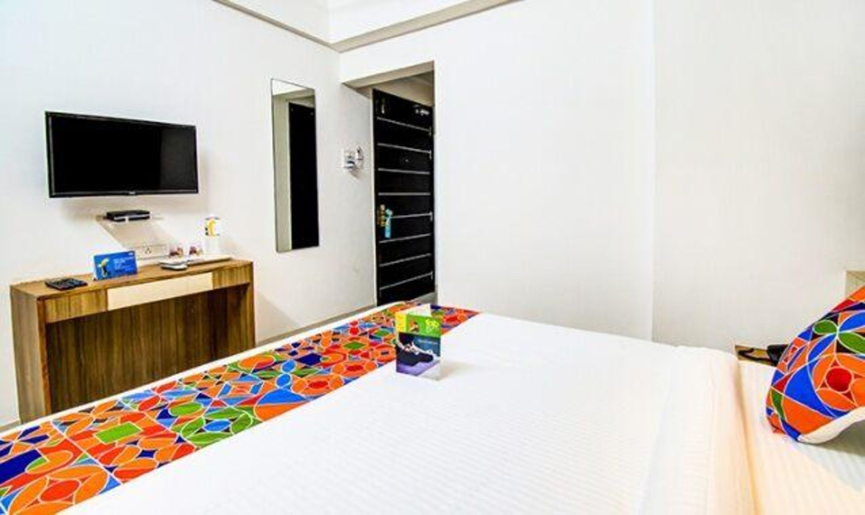 A hotel room with a bed, a TV, a desk, and a wardrobe.