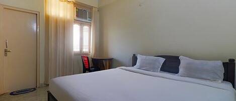Une chambre d’hôtel avec un lit, une chaise, une petite table et une porte.