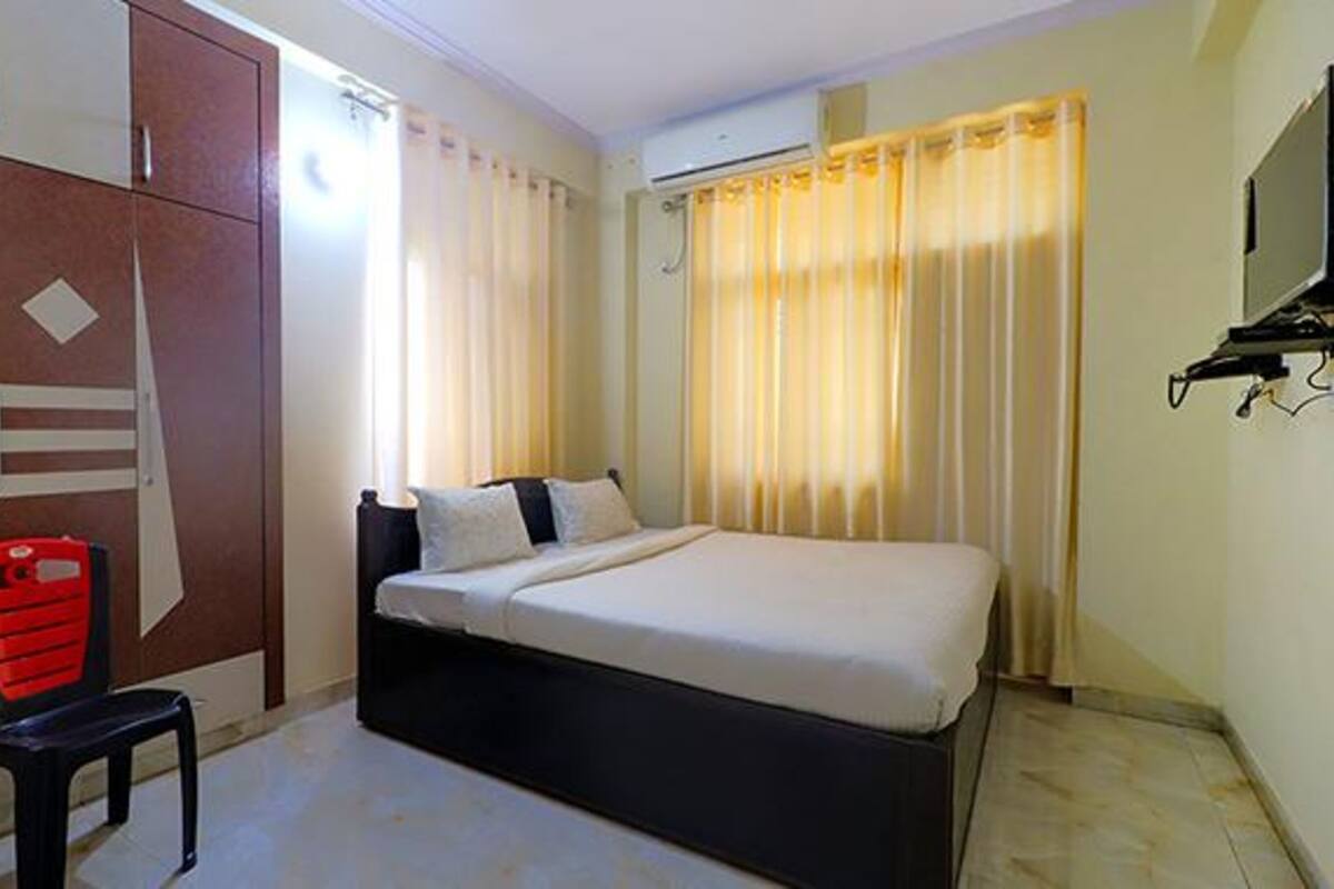 A bedroom with a bed, a wardrobe, a chair, and a TV.