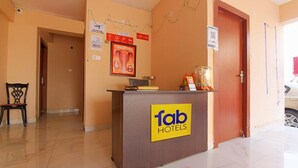 Un comptoir d'accueil avec une enseigne indiquant « fab hotels », une chaise et une porte sur la droite.