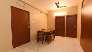Une pièce comprenant une table à manger et des chaises, un ventilateur de plafond et trois portes en bois.