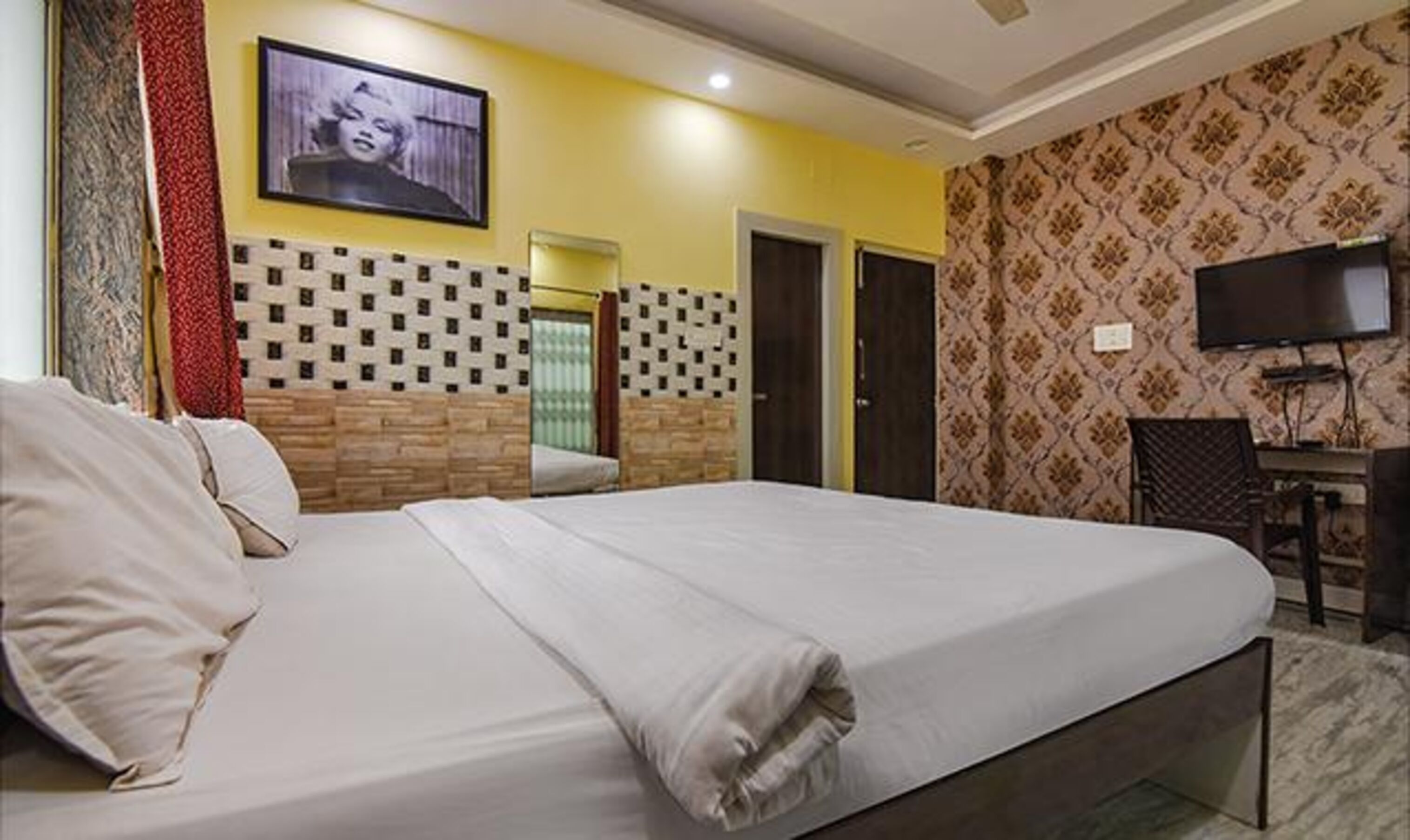 Una habitación de hotel con una cama grande, televisor y un escritorio con silla.