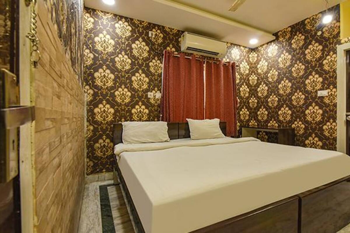 Habitación de hotel con cama, cortinas, equipo de aire acondicionado y papel tapiz estampado.