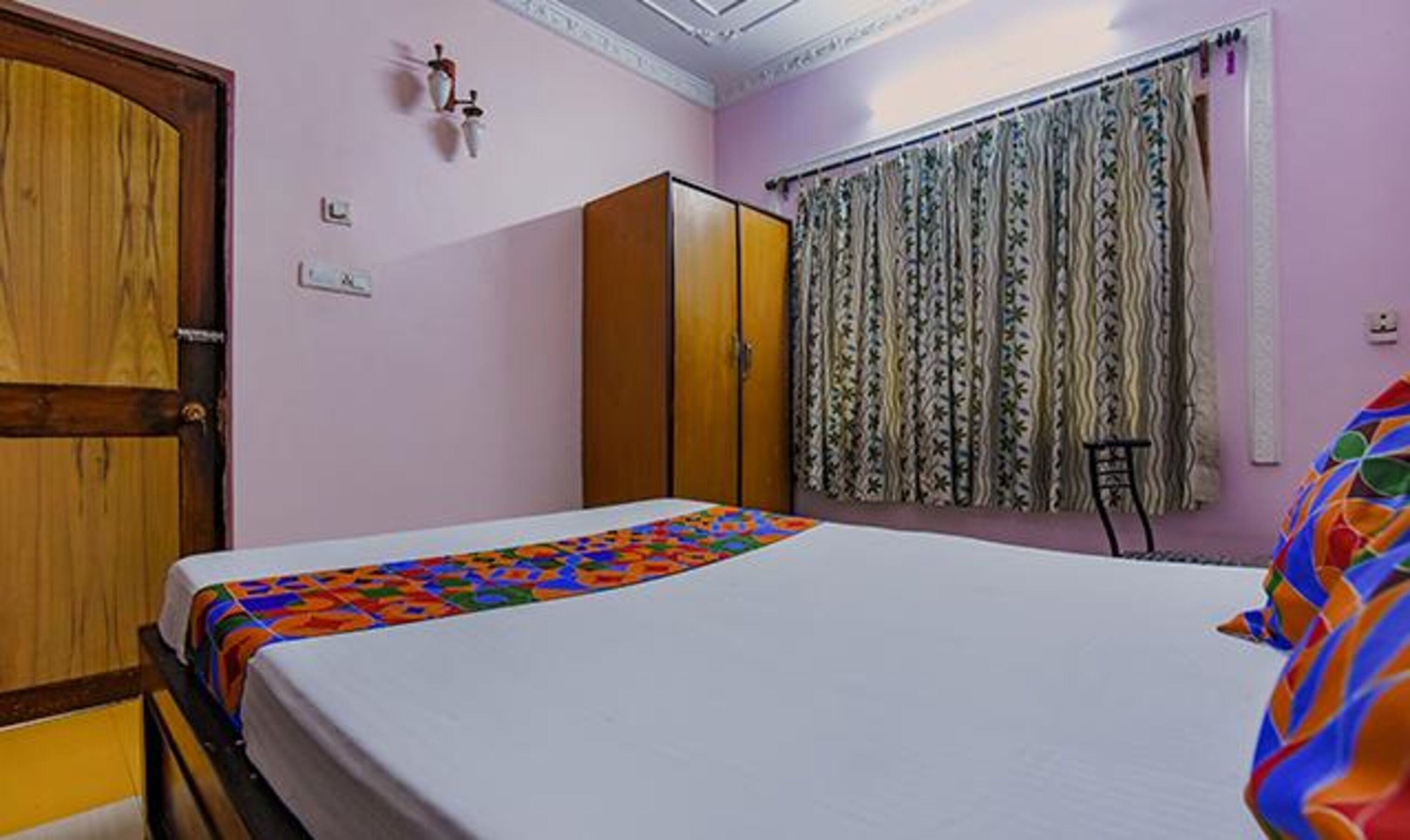 A bedroom with a bed, wardrobe, and curtains.