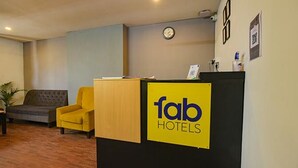 Una recepción con un cartel de 'fab hotels', un reloj y un sofá en el vestíbulo de un hotel.