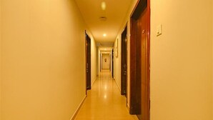 Un largo pasillo de hotel, estrecho, con puertas a ambos lados y suelo de color claro.