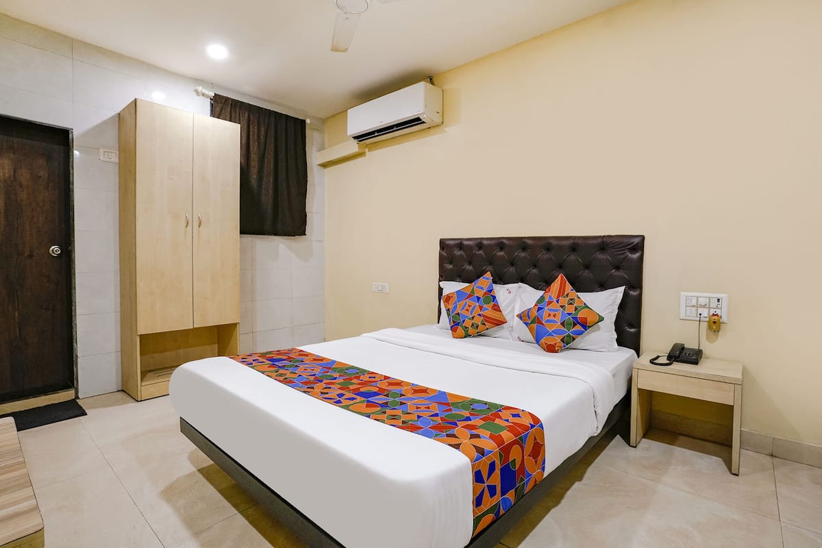 Una habitación de hotel ordenada con cama, mesita de noche y armario.