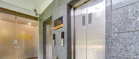 A hotel entrance with a glass door, a sign indicating the hotel code, and an elevator.