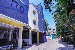 A narrow street with buildings painted in blue and white, a parked car, and a motorcycle.