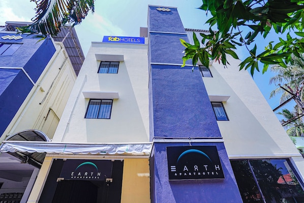 Un edificio de varios pisos con un letrero que indica 'fab Hotels' y 'Earth Apartment Hotel', señalando un hotel y complejo de apartamentos.