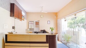 A kitchen with a wooden counter, a ceiling fan, a clock, and a calendar on the wall. - Fabexpress Uv Residency (Coimbatore)