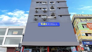 Un hôtel avec une enseigne bleue, plusieurs unités de climatisation et une vitrine ornée de mannequins.