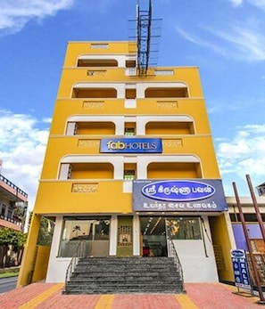 A multi-story building with a yellow facade, a sign for 'Fab Hotels', and a sign in a local language. - Fabhotel Radha Residency (Vanur)
