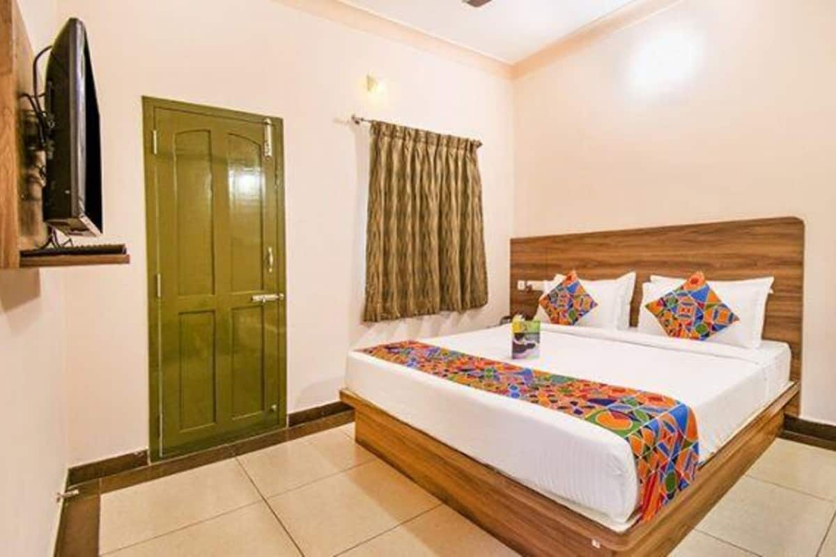 A hotel room with a wooden bed, a green door, and a curtain.