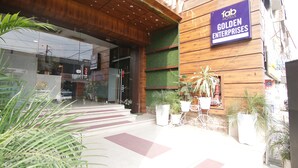 The exterior of a hotel with a wooden facade, a sign for 'Fab Hotels Golden Enterprises', and potted plants in front. - FabHotel Golden City (Amritsar)