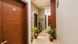 A hallway with wooden doors, numbered 102, and potted plants along the walls. - FabHotel Golden City (Amritsar)