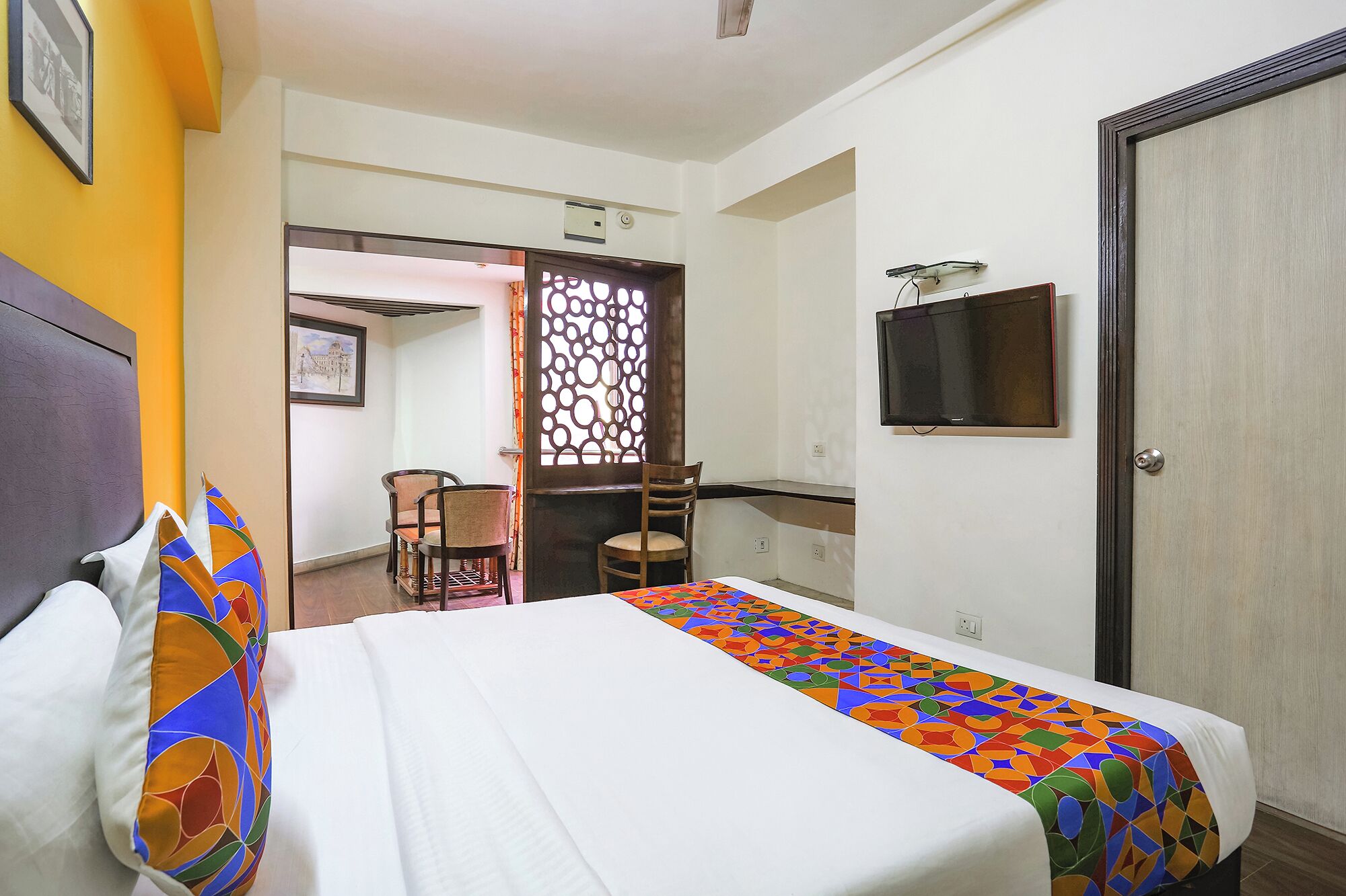 A hotel room with a bed, a desk, a chair, and a wardrobe.
