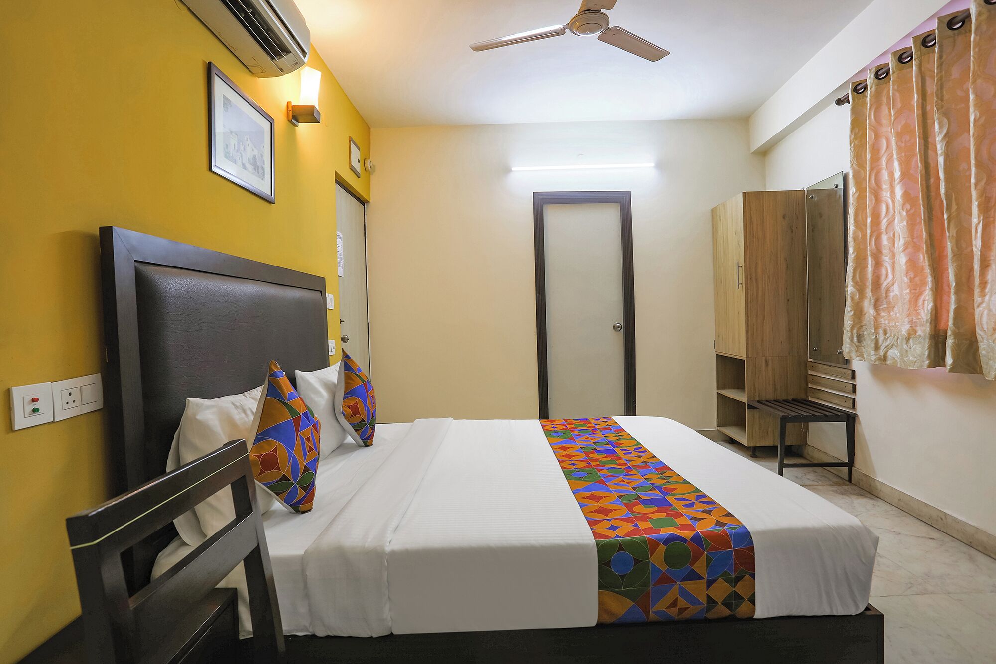 A hotel room with a bed, a wardrobe, a ceiling fan, and a door.