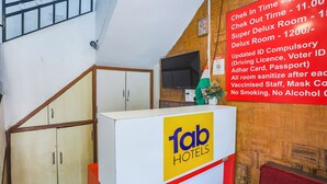 A hotel reception desk with a sign listing room rates and COVID-19 safety measures. - Fabexpress Jai Manglam Service Apartment (Nagpur)