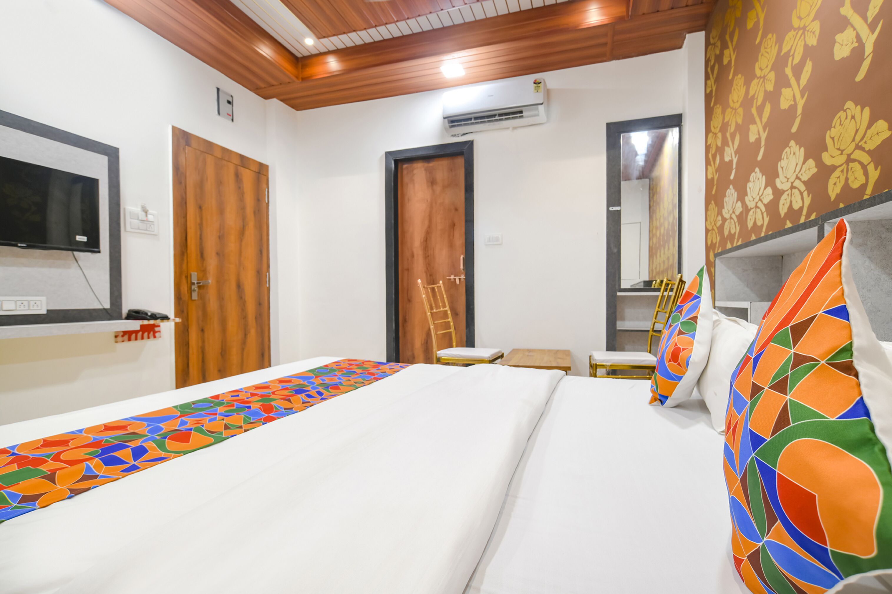 Une chambre d’hôtel avec un lit, une télévision, une porte en bois et un miroir.