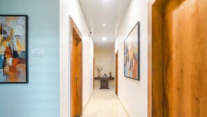 A hallway with a marble floor, wooden doors, and framed artwork on the walls. - FabHotel Dream Paradise (Indore)