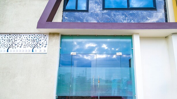 A modern building with a large glass door, a tree mural on the wall, and a clear view of the sky through the glass. - FabHotel Dream Paradise (Indore)