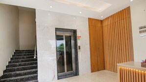 Um lobby moderno com uma escadaria de mármore, um balcão de recepção e uma parede revestida de madeira.