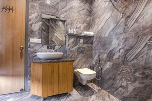 A modern bathroom with a marble backsplash, wooden vanity, and a toilet with a handheld shower. - Fabhotel Prime Taj Castle (Amritsar)