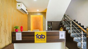A hotel reception desk with a wooden finish, a reception counter, and a staircase leading to an upper floor.