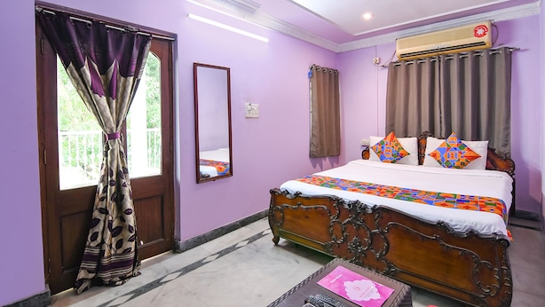 A bedroom with a bed, a ceiling fan, and an air conditioning unit. - Fabexpress Karunamoyee Regency (Barasat)