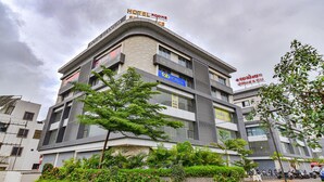 A hotel with multiple floors, balconies, and a sign indicating hotel rooms. - Fabhotel Sky Palace (Surat)