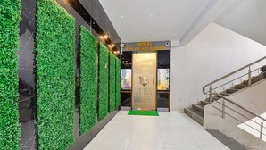 A hotel lobby with a green wall, a staircase, and a sign reading "HOTEL SKY PALACE ROOMS". - Fabhotel Sky Palace (Surat)