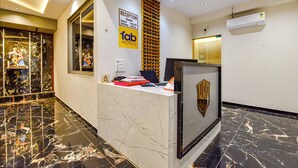 A reception desk with a marble floor, a reception sign, and a wall-mounted air conditioner. - Fabhotel Sky Palace (Surat)