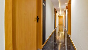 A hotel hallway with wooden doors, a marble floor, and a number sign on the wall. - Fabhotel Sky Palace (Surat)