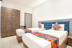 A hotel room with two beds, a large wardrobe, and a blue headboard. - Fabhotel Jr Residency I (Navi Mumbai)
