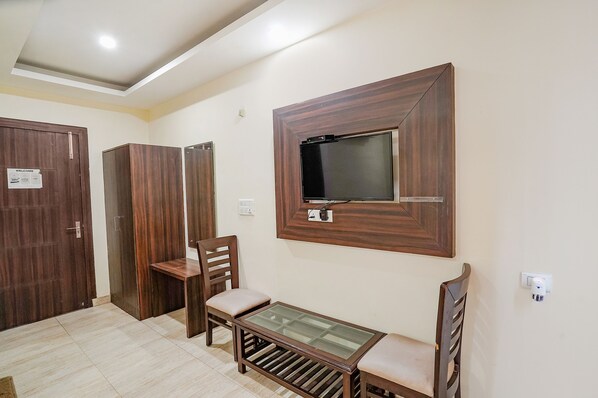 A room with a wooden wardrobe, a wooden chair, a glass-top table, and a mounted TV. - FabHotel Comfort Stay Vaishali - 300m from Chandra Laxmi Hospital, Ghaziyabad Ghaziabad (Ghaziabad)