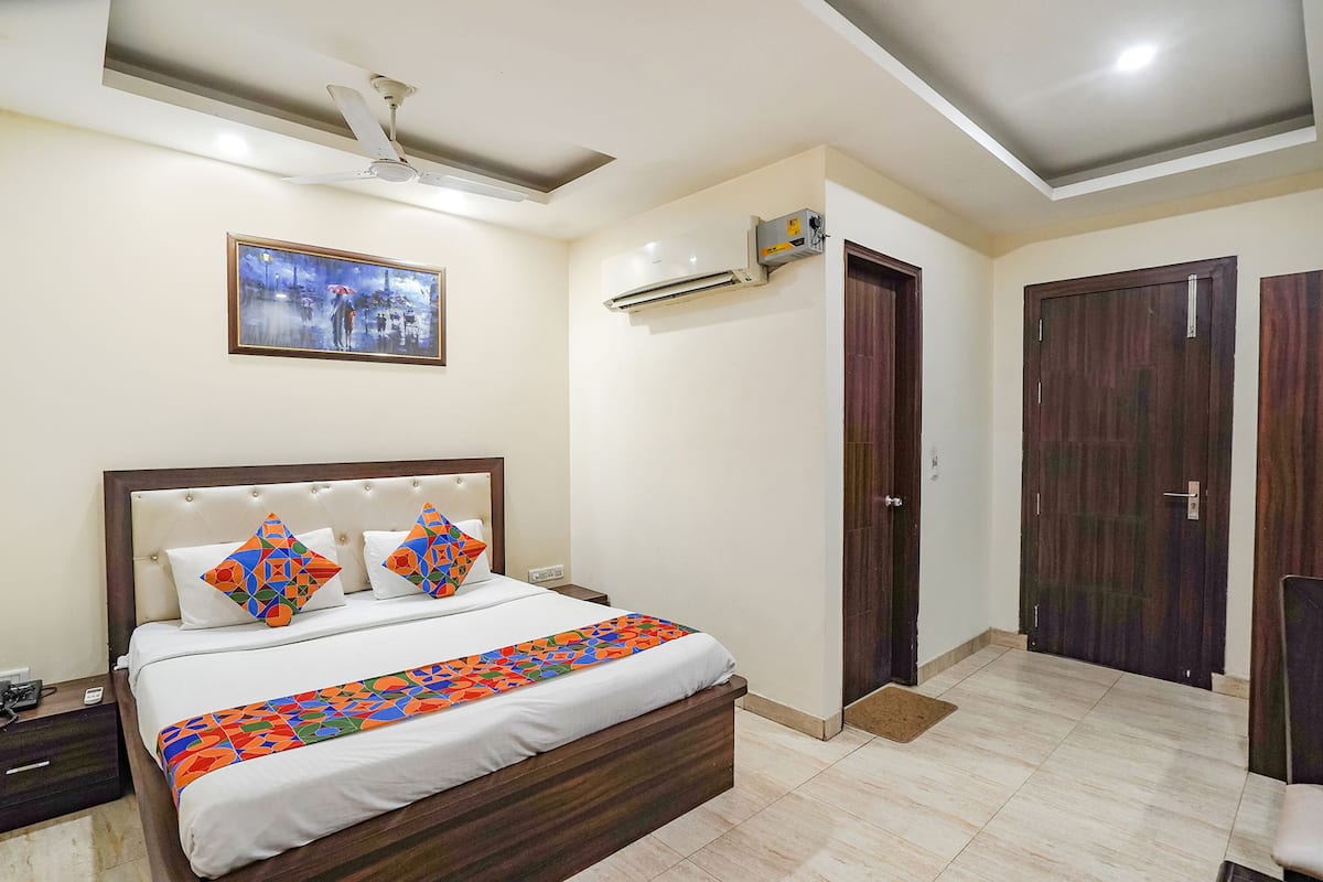 Un dormitorio con cama, mesita de noche, aire acondicionado, ventilador de techo y una puerta.