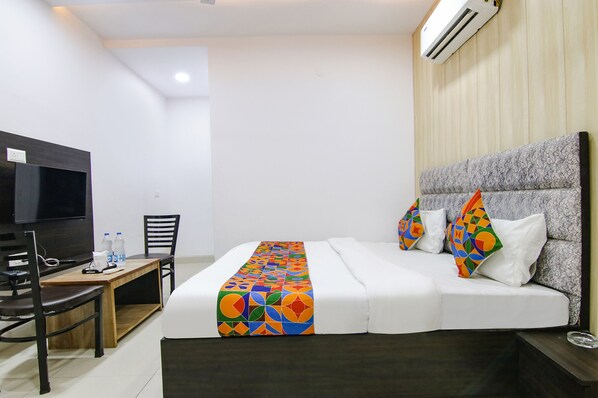 A hotel room with a bed, a TV, a desk, and a chair.