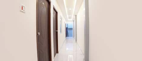 A corridor with doors, a fire alarm, and a staircase at the end.