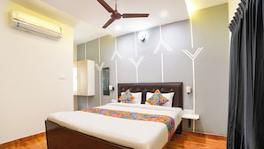 Un dormitorio con cama, ventilador de techo, aire acondicionado, mesita de noche y lámpara de pared.