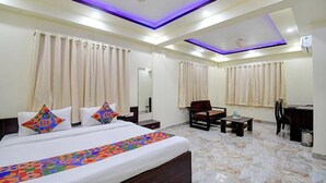 A hotel room with a bed, a desk, a chair, and a small table.